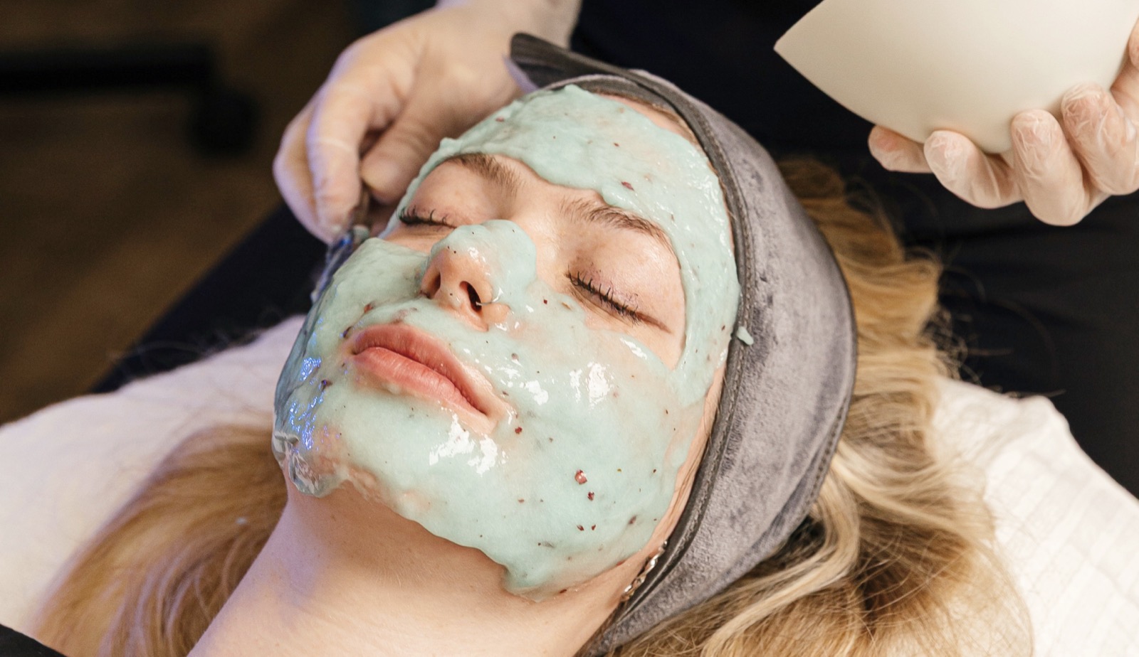 Green facial mask application during a facial at Ageless Esthetics Calgary